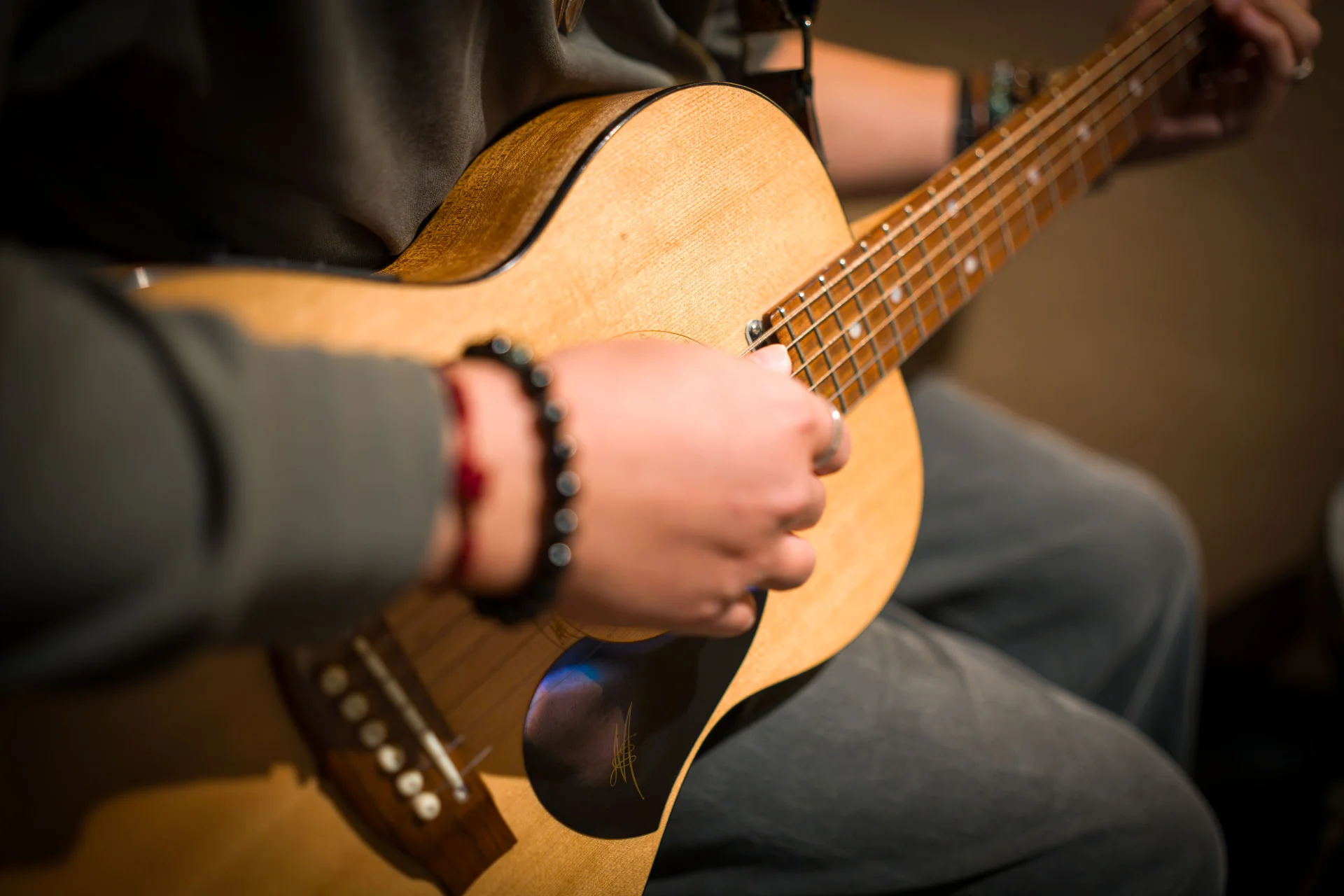Close-up of hands playing an acoustic guitar in a warm, intimate music therapy setting