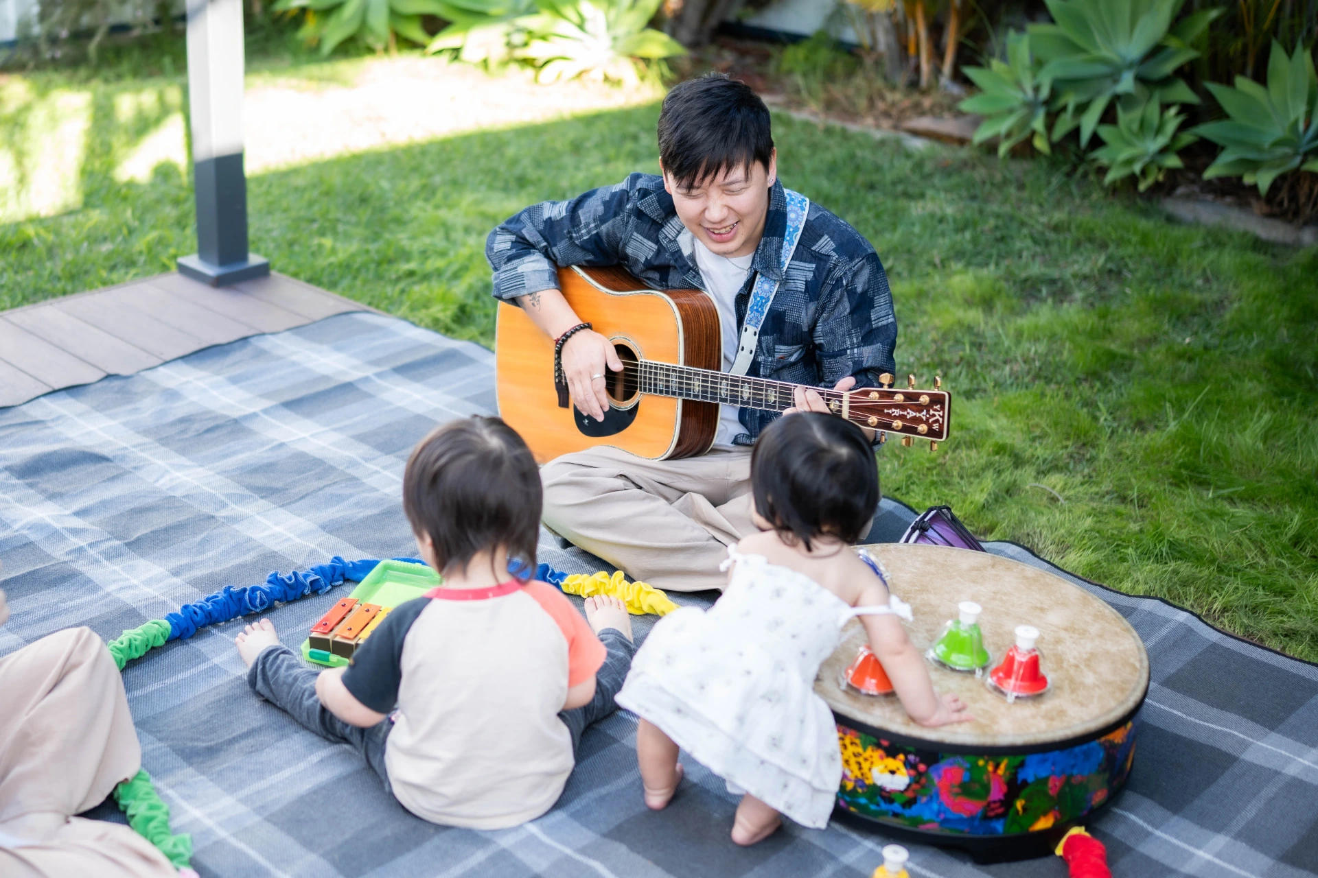 Music therapist playing guitar outdoors with young children during a play-based session
